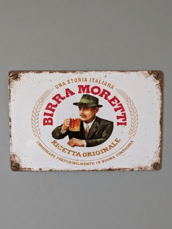 Horizontal vintage-style metal wall sign for Birra Moretti, featuring an illustration of a man with a moustache in a suit and green hat drinking a beer, surrounded by red 'BIRRA MORETTI' typography and 'RICETTA ORIGINALE' text on a distressed white background.