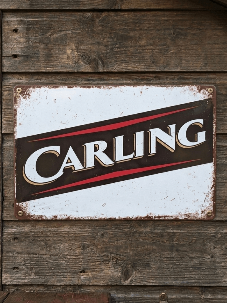 Horizontal vintage-style metal wall sign for Carling lager, featuring the bold white 'CARLING' typography on a black and red diagonal banner, set against a distressed white background and mounted on a weathered wooden wall.