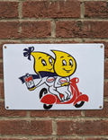 Horizontal white metal wall sign featuring two yellow Esso oil drop cartoon characters riding a red motor scooter; one character holds a vintage Esso oil can. The sign is mounted on a red brick wall with four brass screws.