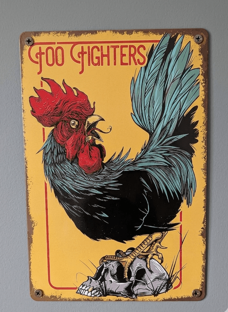 Vertical metal wall sign featuring the Foo Fighters logo with an illustration of a black and teal rooster standing on a human skull against a yellow background with rusted edges.