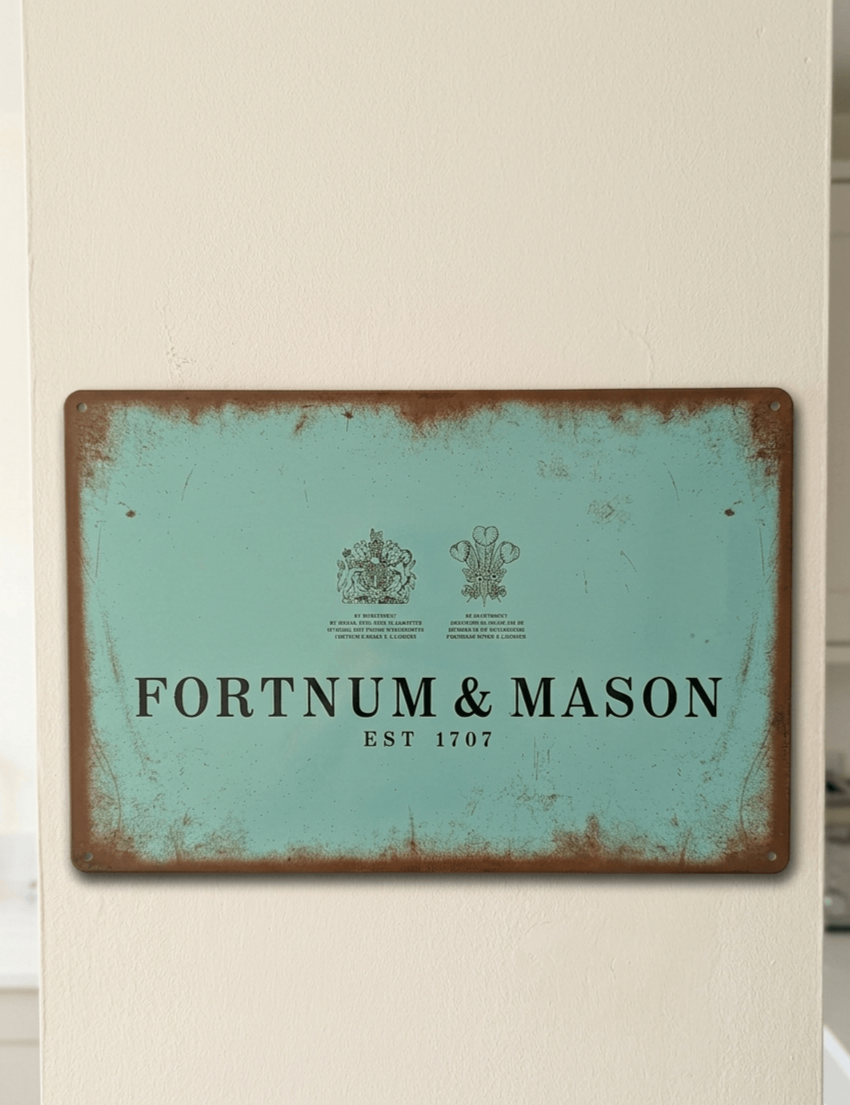 Vintage-style landscape metal wall sign for Fortnum & Mason in their signature Eau de Nil blue, featuring the brand name, 'EST 1707', and Royal Warrants with heavily rusted, weathered edges.