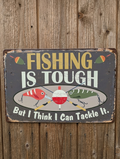 Vintage-style landscape metal wall sign with the text 'FISHING IS TOUGH But I Think I Can Tackle It' featuring colorful fishing lures and a bobber on a distressed dark background with rusted edges
