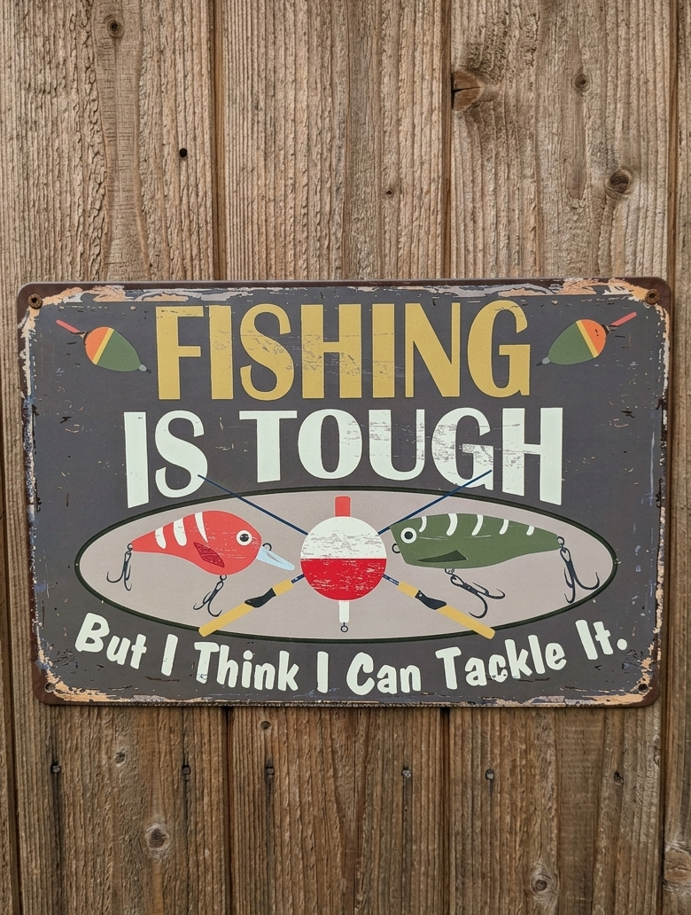 Vintage-style landscape metal wall sign with the text 'FISHING IS TOUGH But I Think I Can Tackle It' featuring colorful fishing lures and a bobber on a distressed dark background with rusted edges