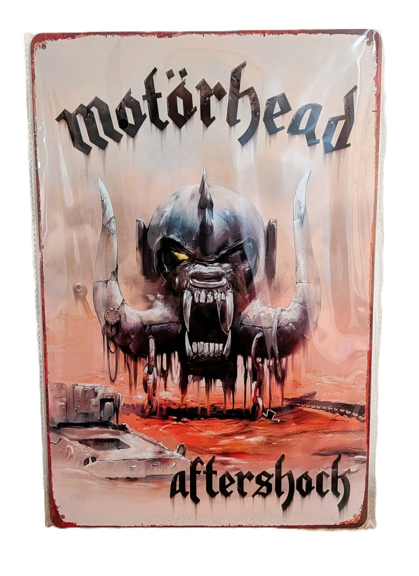 Vertical metal wall sign for the Motörhead album 'Aftershock,' featuring a high-detail illustration of the Snaggletooth mascot with large tusks over a war-torn landscape, with the band name and album title in gothic black script.