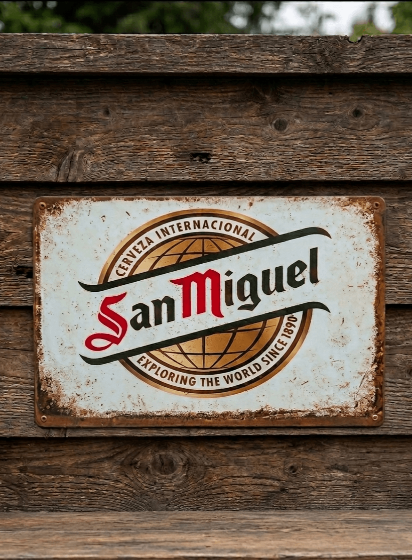 Landscape-oriented metal wall sign for San Miguel beer, featuring the 'Cerveza Internacional' globe logo and 'Exploring the world since 1890' text on a heavily distressed white background.