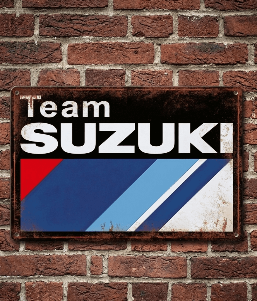 Vintage-style landscape metal wall sign featuring the Team Suzuki logo with red, blue, and light blue diagonal racing stripes and a heavily rusted, distressed border