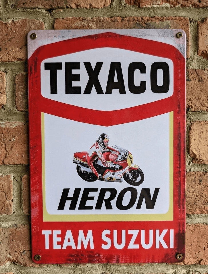 Vertical vintage-style metal wall sign for Texaco Heron Team Suzuki, featuring a racing motorcycle with rider, the Texaco logo, and 'Heron Team Suzuki' text on a distressed white and red background.