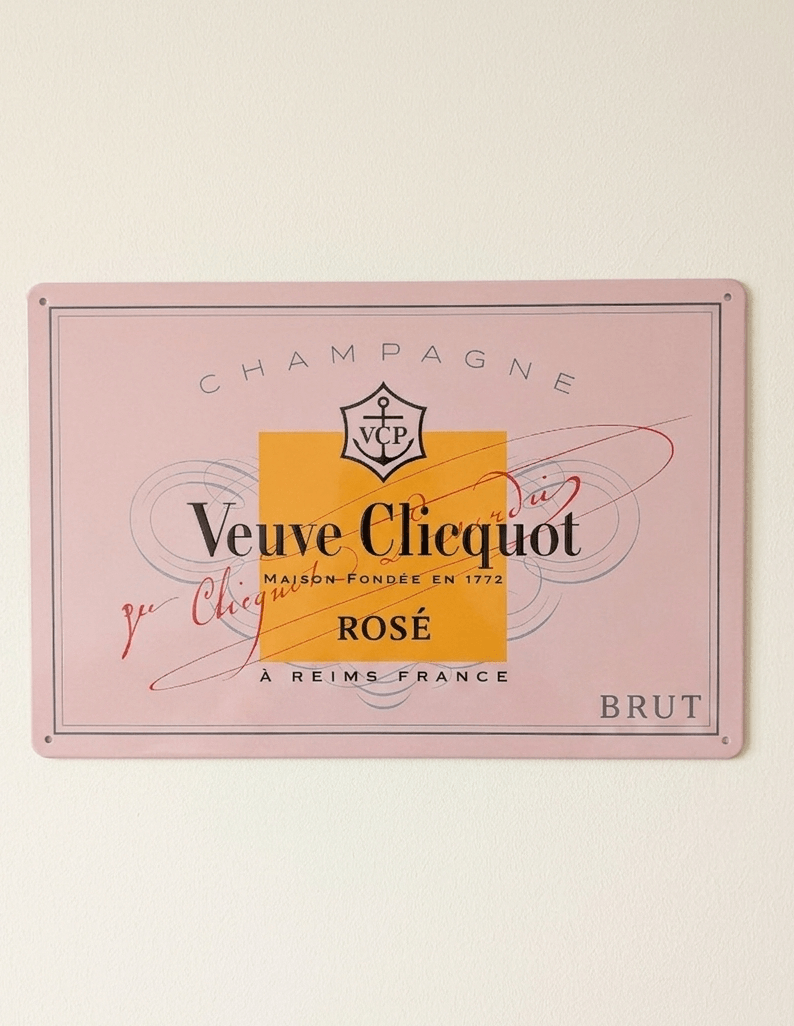 Horizontal pink metal wall sign for Veuve Clicquot Rosé Champagne, featuring the brand's iconic orange-yellow square, anchor logo, and elegant black and red typography on a soft pink background.