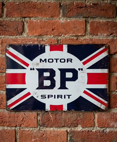 Vintage-style landscape metal wall sign for BP Motor Spirit featuring the Union Jack flag and classic BP shield logo on a distressed white background with rusted edges.