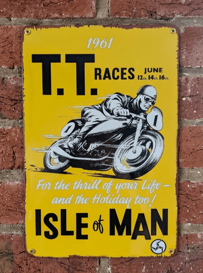 Vintage-style vertical yellow metal wall sign for the 1961 Isle of Man T.T. Races, featuring a stylized motorcycle racer in action with the slogan 'For the thrill of your Life – and the Holiday too!' and rusted edges.