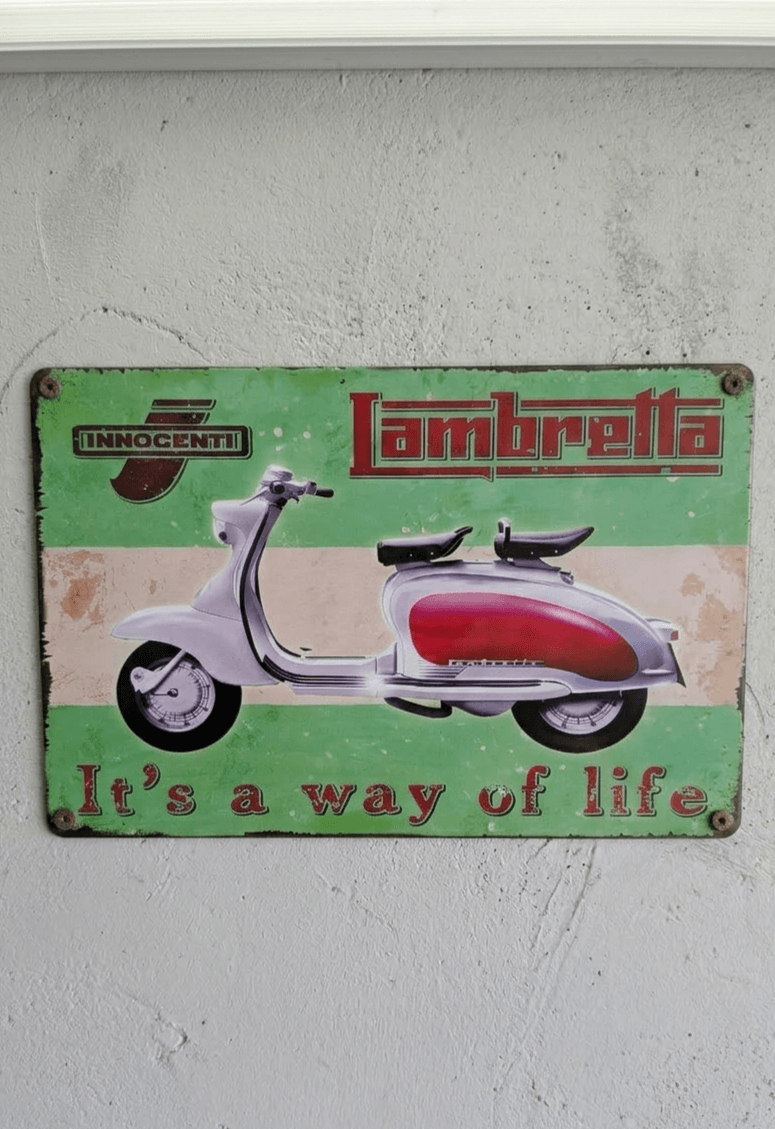 Vintage-style green and white metal wall sign for Lambretta scooters, featuring a classic silver and red scooter with the slogan It's a way of life and a distressed, rusted border