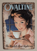 Vertical vintage-style metal wall sign for Ovaltine, featuring a mid-century painted illustration of a smiling woman holding a white teacup and saucer by a window at night, with light blue branding at the top and text reading 'The World's Best Nightcap' against heavily rusted borders.