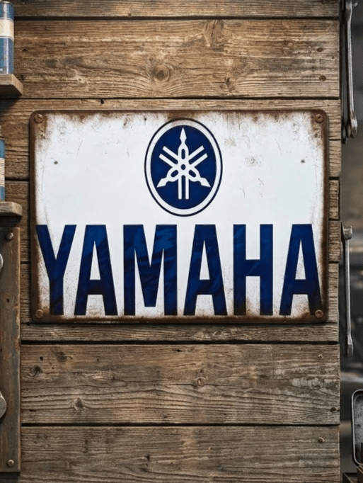 Vintage-style landscape metal wall sign for Yamaha, featuring the iconic tuning fork logo in a blue circle above bold blue 'YAMAHA' text on a distressed white background with rusted, weathered edges.